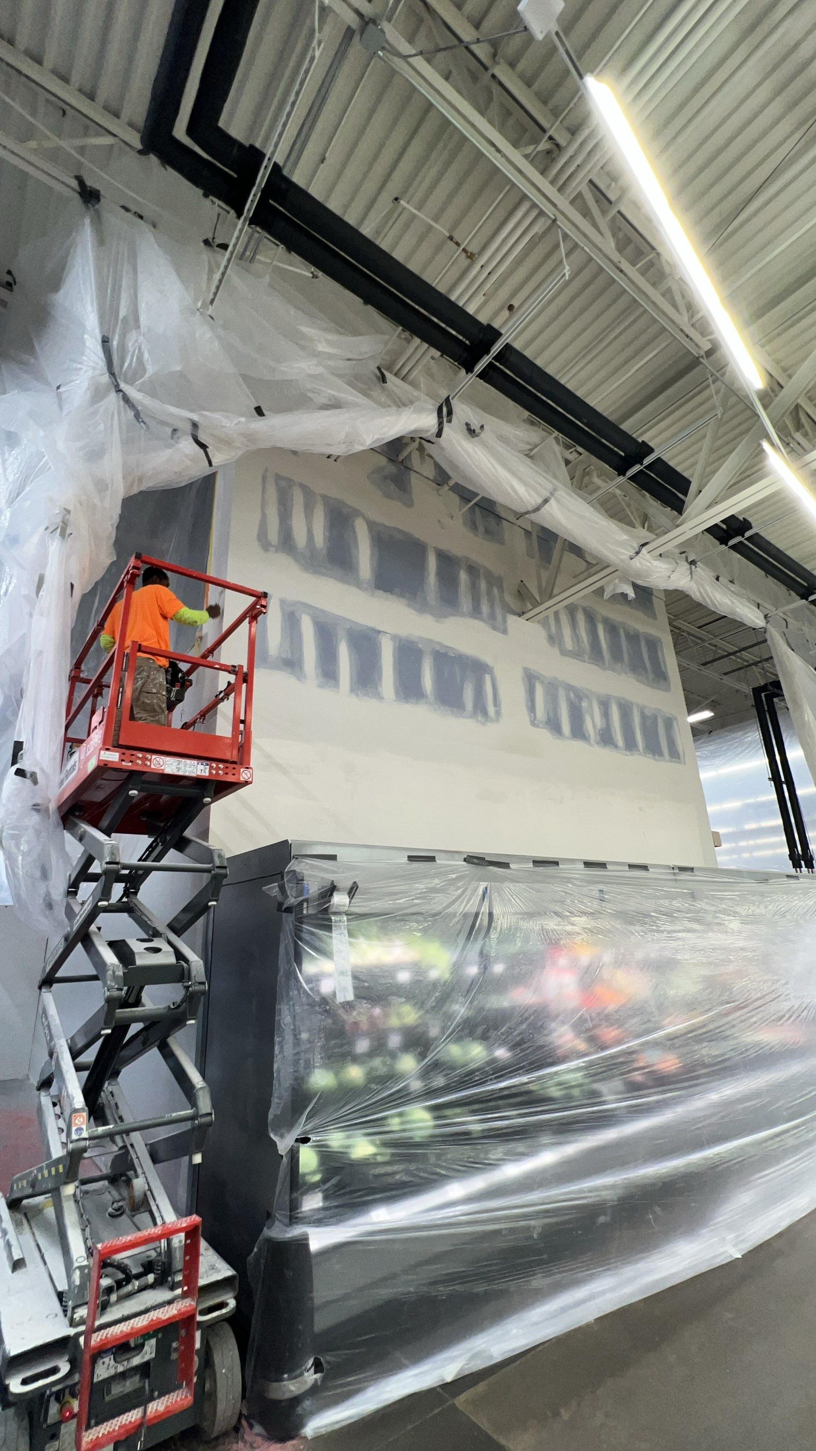 Painter applying a wall coating from a lift in a protected work zone