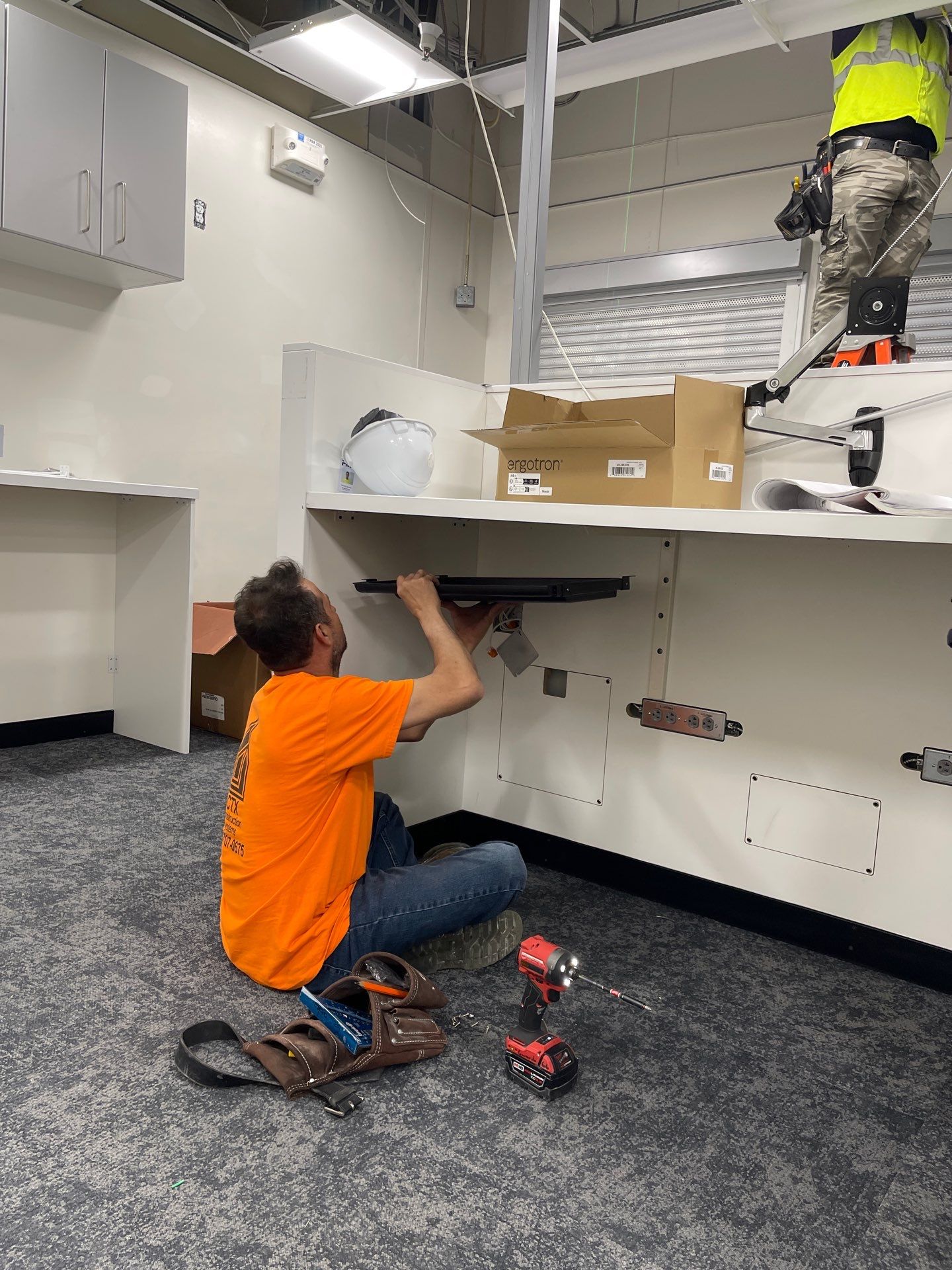 Carpenter installing equipment beneath a retail service work surface