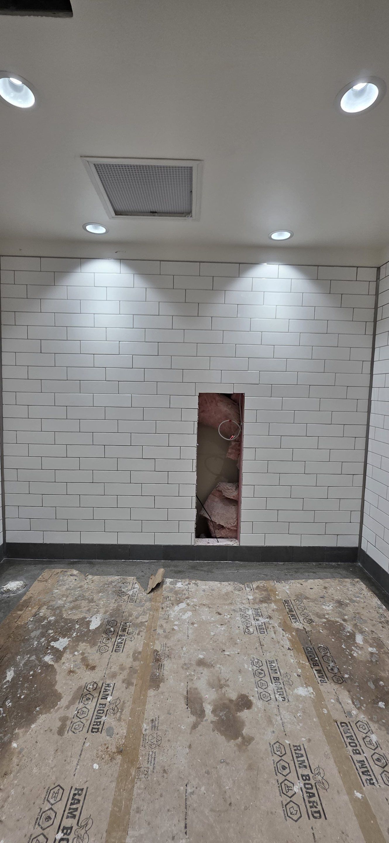White subway tile installed across a restroom wall beneath recessed lighting